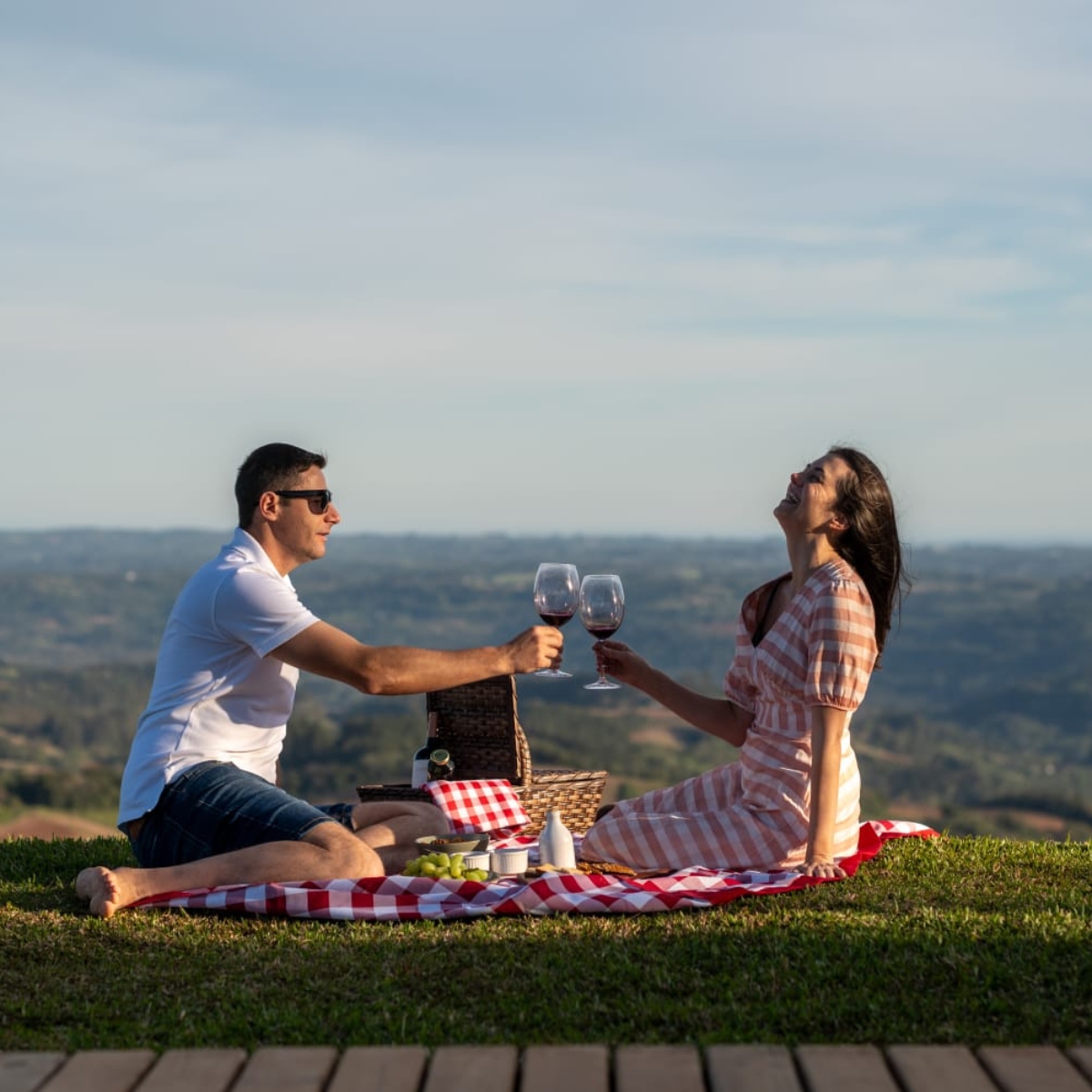 Casal sorrindo em piquenique romântico no topo da colina