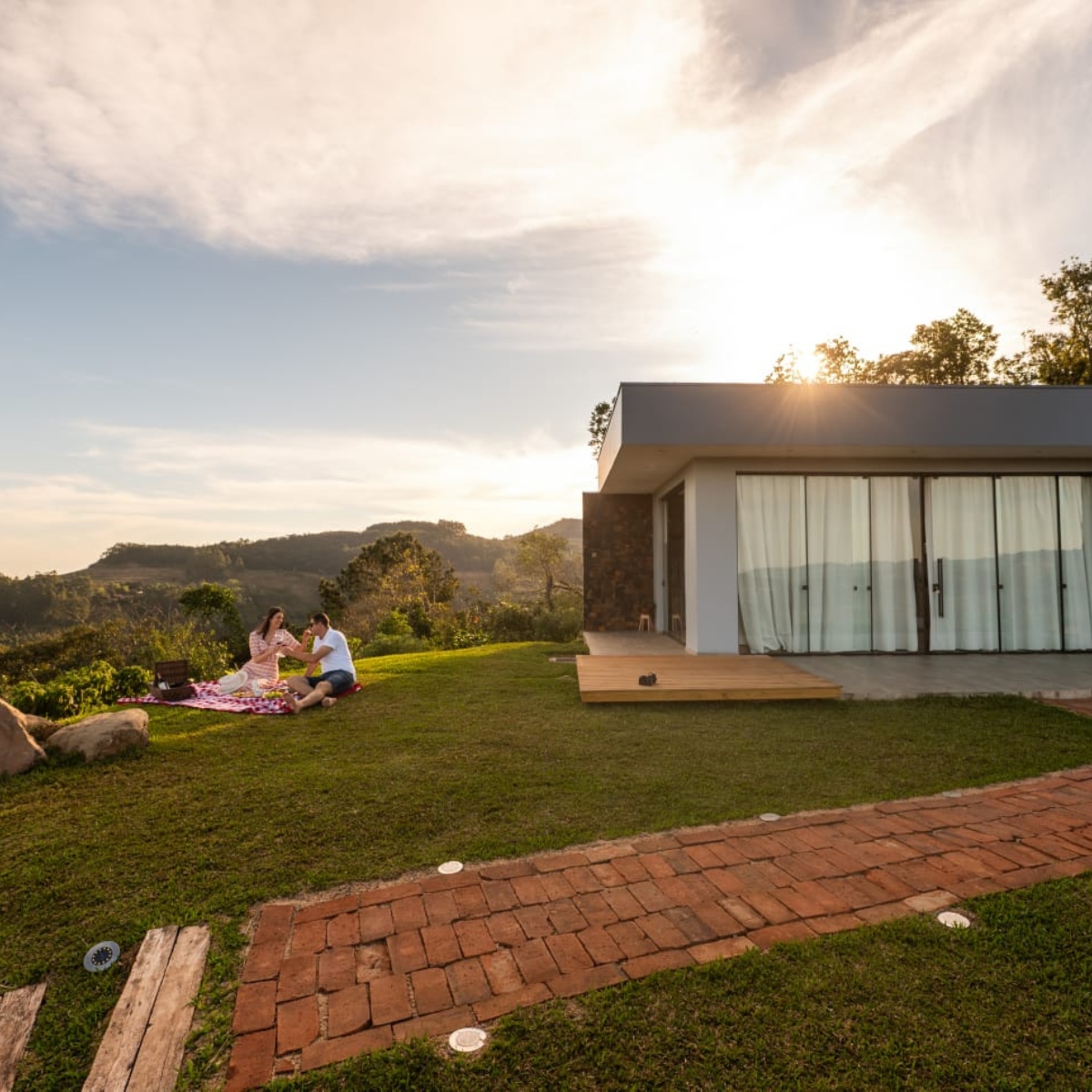 Casal em piquenique romântico no gramado da cabana ao pôr do sol em Santa Cruz do Sul