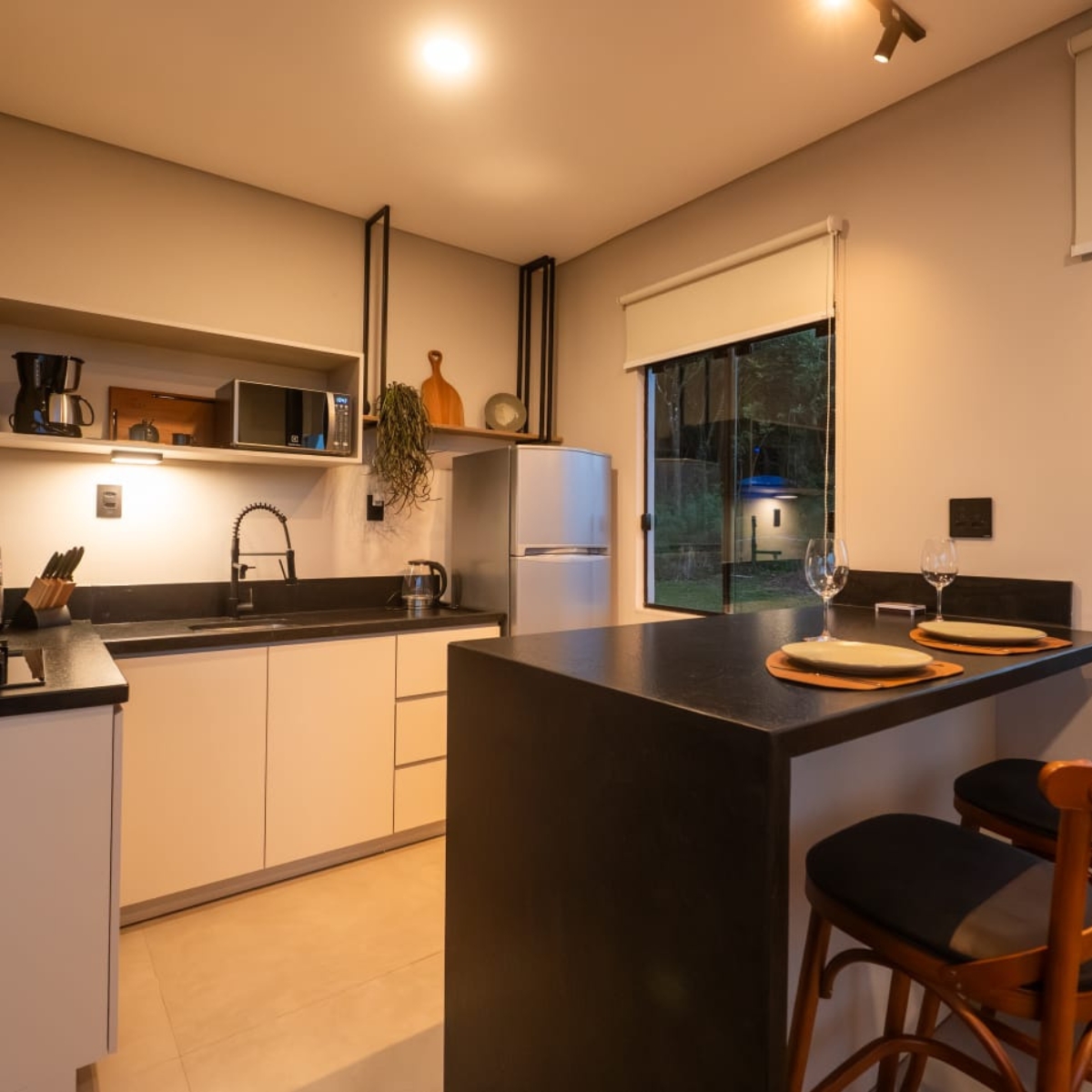 Cozinha gourmet à noite com vista para a área externa da cabana