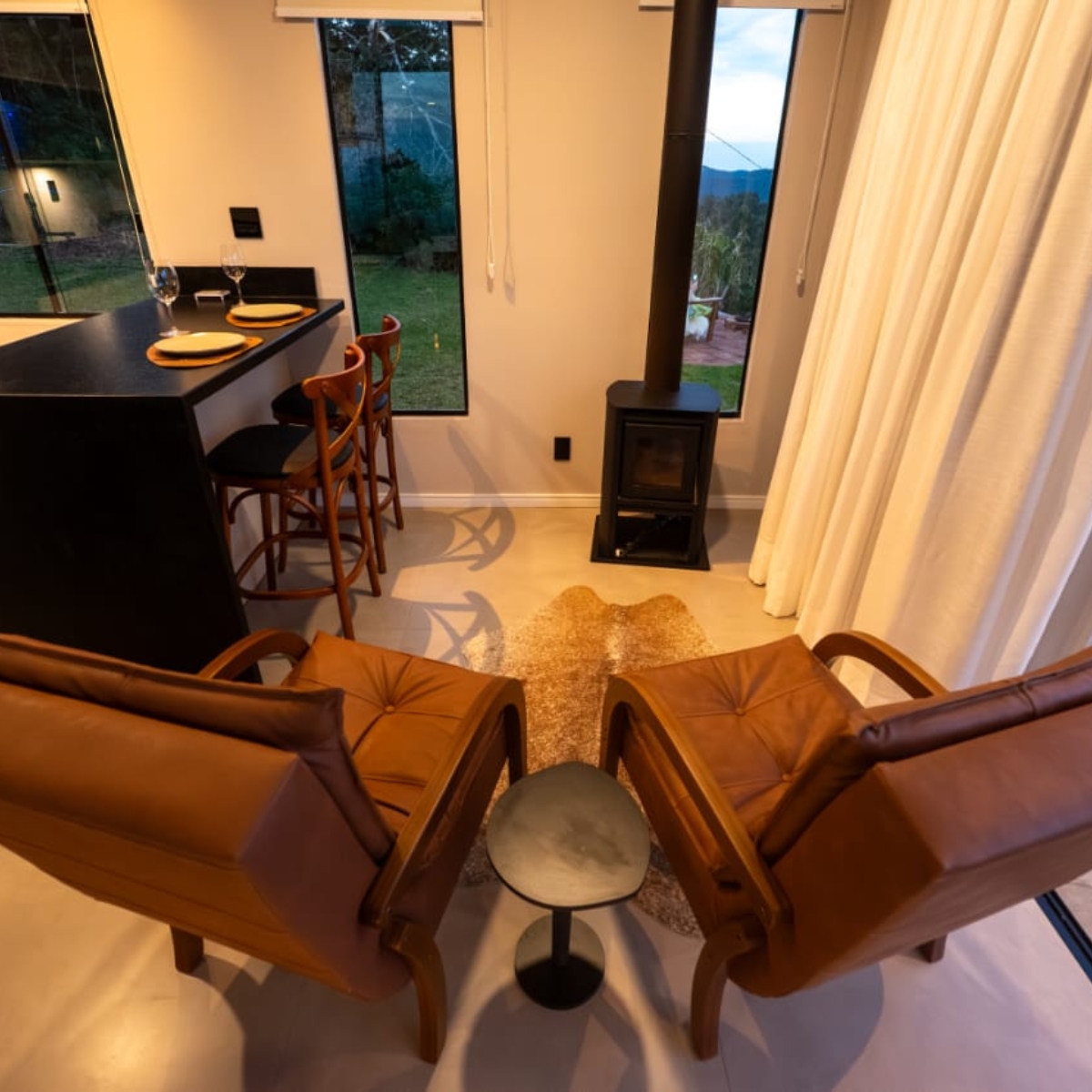 Sala de estar com lareira a lenha e poltronas de couro