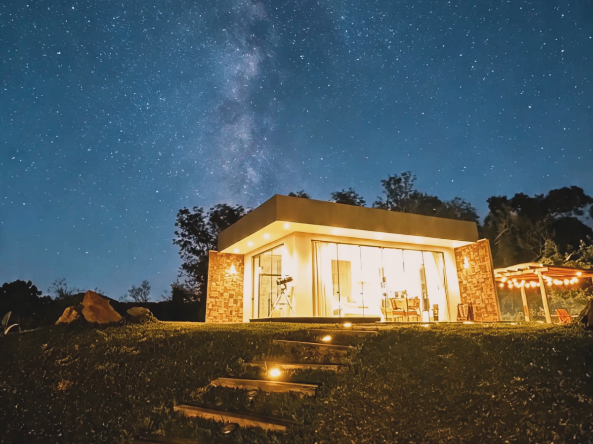 Cabana Lúmina Colina iluminada sob céu estrelado à noite